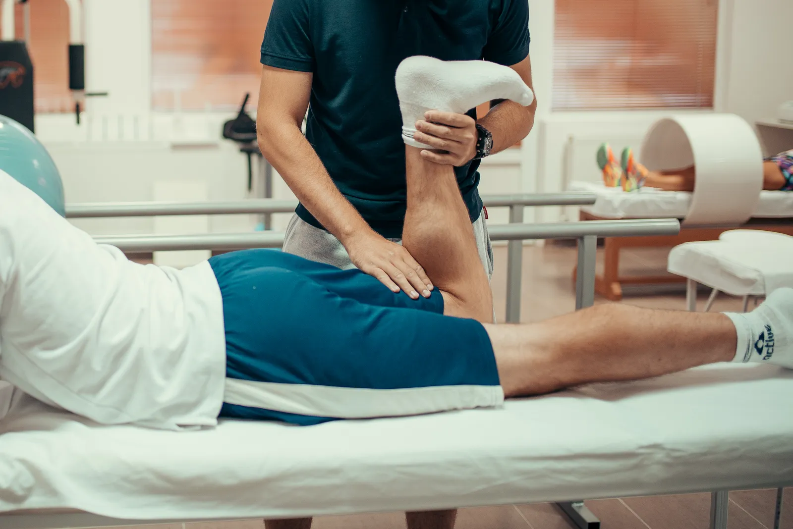 A physiotherapist stretching a patient's leg during a rehabilitation session